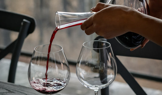 Red wine decanter in an outside setting with wine glasses